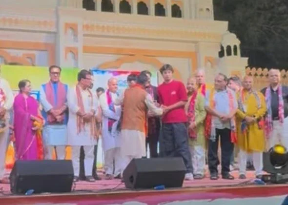 Aarav in a red T-shirt on stage being presented the FORTI Youth Ambassador award