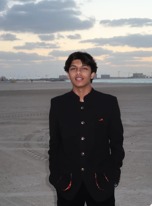 Aarav Sacheti in a black bandhgala on a beach at dusk